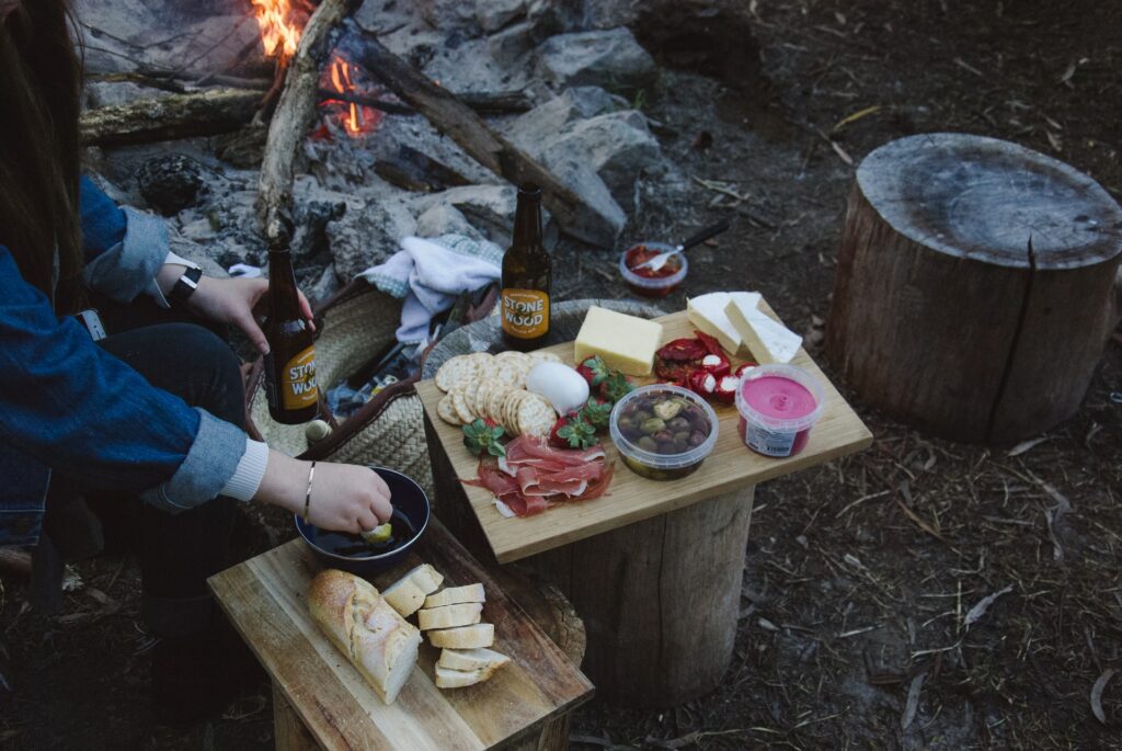 A charcuterie board next to a campfire. One of the best Valentine's ideas for outdoorsy couples: go on a backcountry dinner date