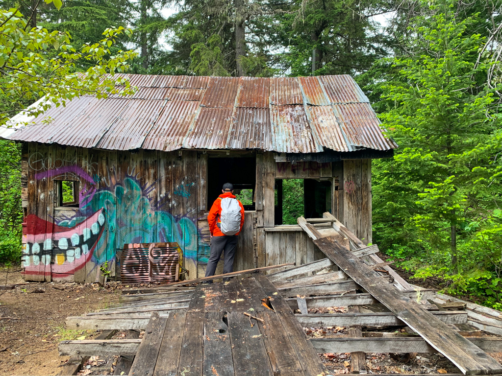 A hiker peers in the window of an abandoned building at the Parkhurst ghost town in Whistler