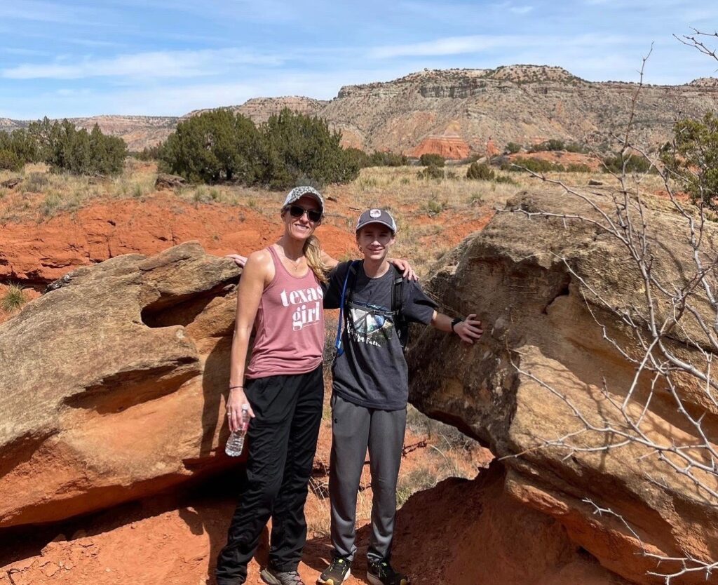 A woman wearing The North Face Aphrodite 2.0 Pants poses with a friend on a hiking trail
