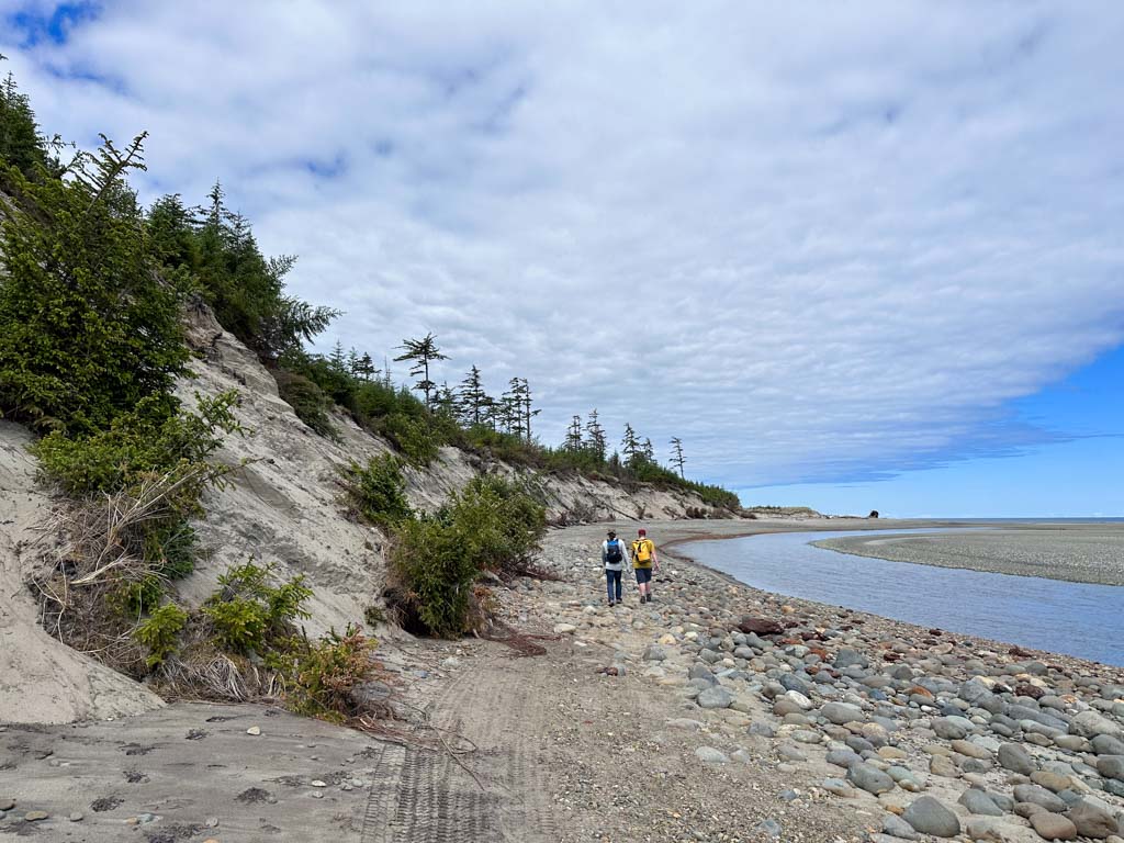 Two hikers walk on the beach on the Pesuta Shipwreck Trail