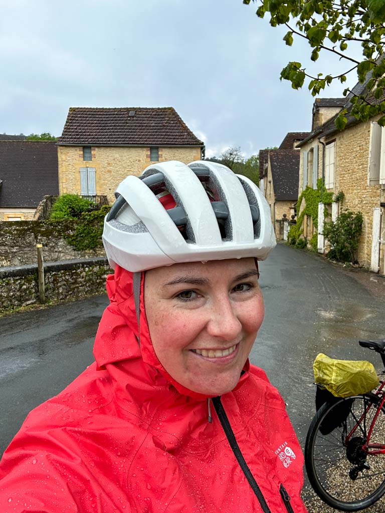 A woman wears a Mountain Hardwear Minimizer rain jacket and a bike helmet in the pouring rain.