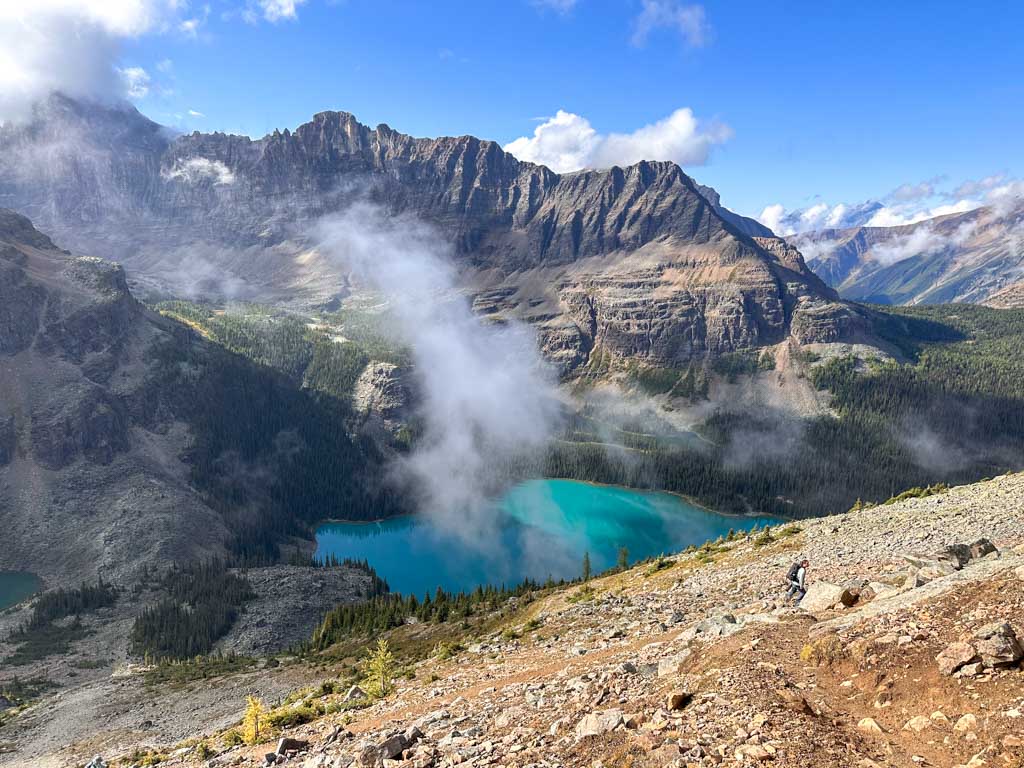 A hiker climbs up a scree slope on the trail to Wiwaxy Gap
