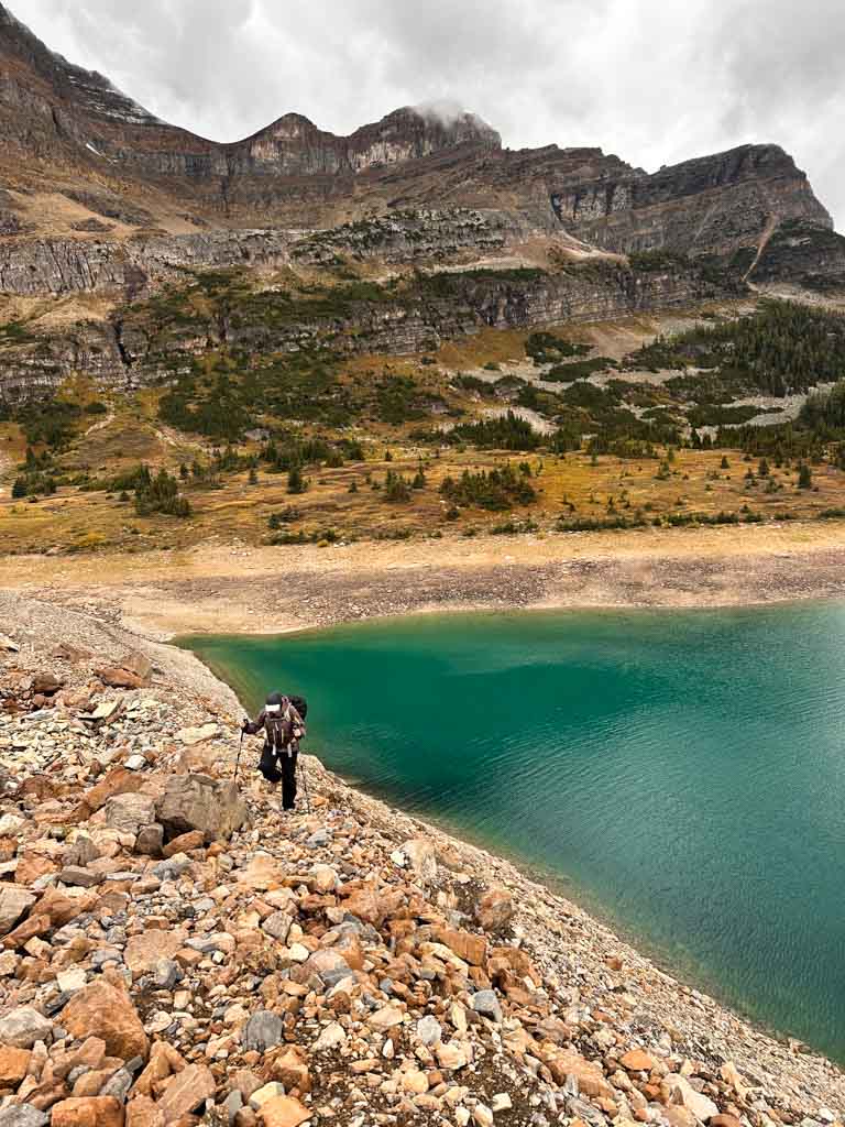 A hiker walks along the shoreline at the back of Lake Magog