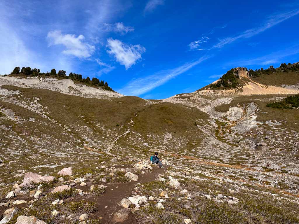 A hiker takes a break on the way up to the saddle between the Gargoyles and Columnar Peak