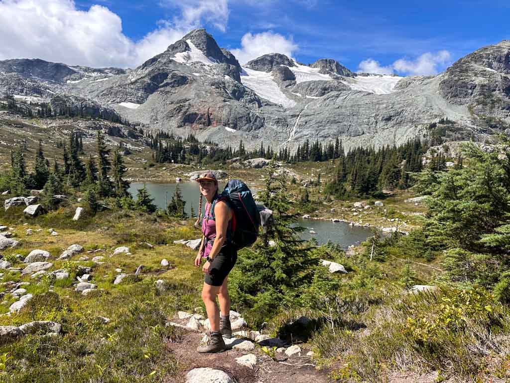 A hiker in front of alpine lakes and glaciers at Semaphore Lakes in Pemberton, BC