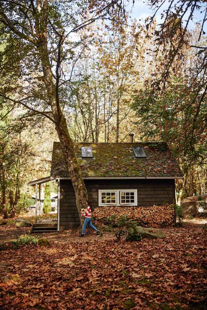 A woman walks past a wood pile at Sunwolf Riverside Cabins in Squamish