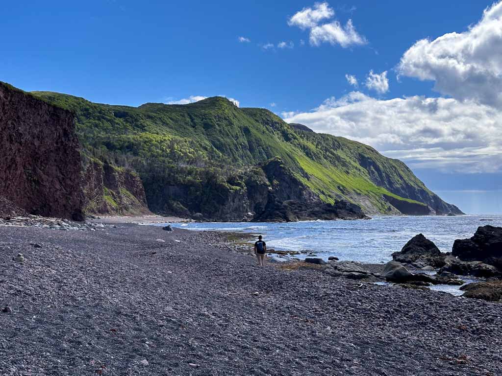 A man hikes on a rocky beach on the Green Gardens Trail in Gros Morne National Park in Newfoundland