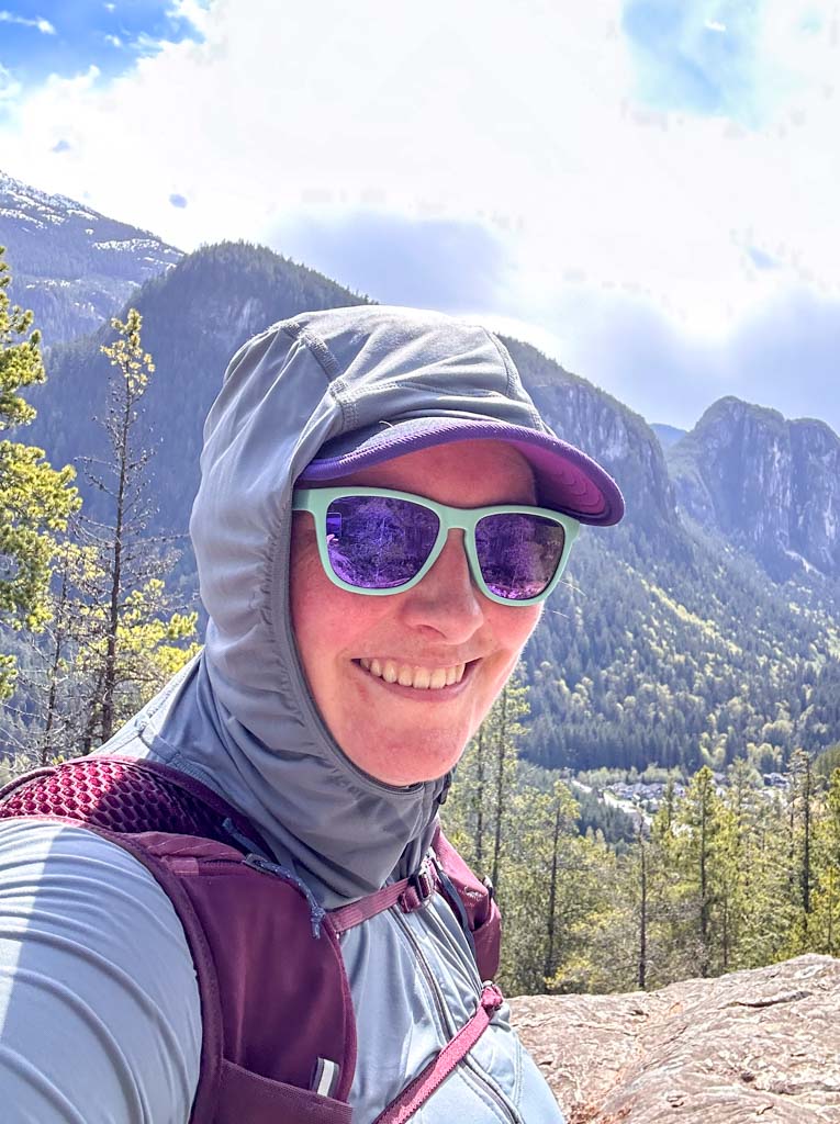 A close up of a hiker wearing a Black Diamond Alpenglow Pro Sun Hoodie with the hood up