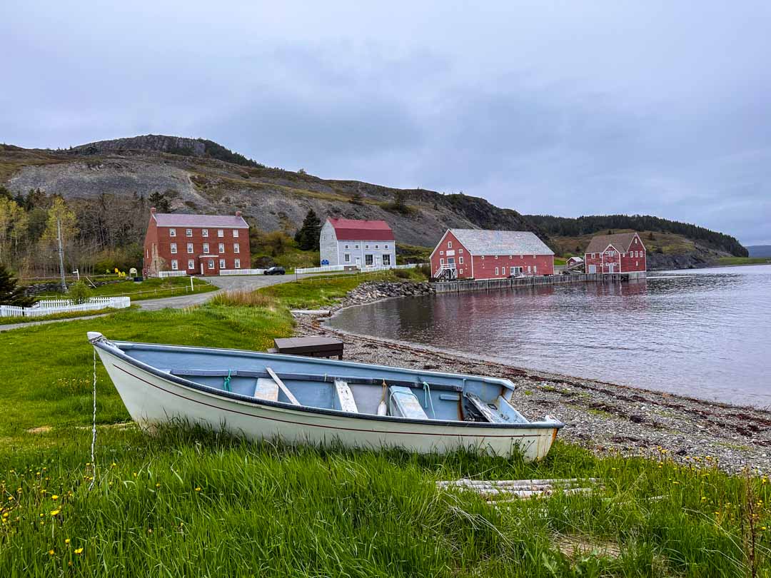 A boat sits in the grass in front of the Lester-Garland Premises, one of the best things to do in Trinity, Newfoundland