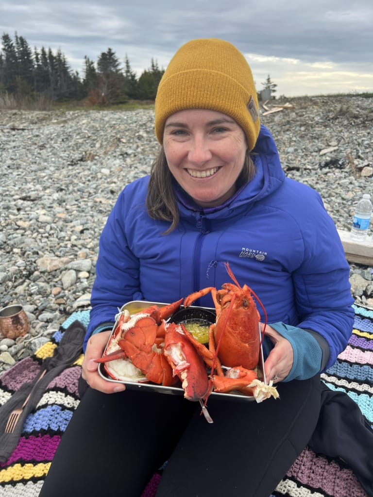 A woman holds a tray of lobster on the beach