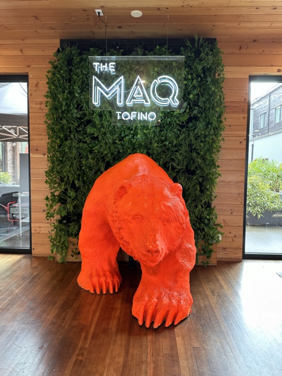A giant orange bear sculpture emerges from a wall underneath a sign reading "The MAQ Tofino" at the Bear Bierhouse