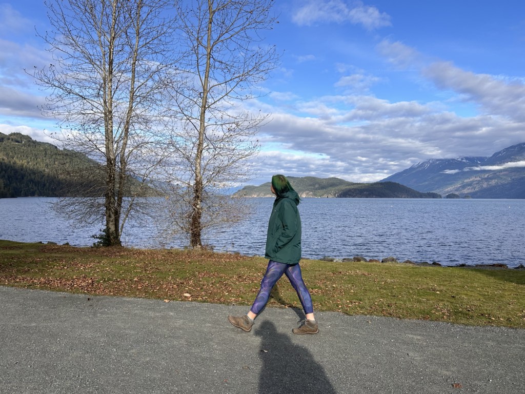 A woman in a green coat walking along the Esplanade in Harrison Hot Springs