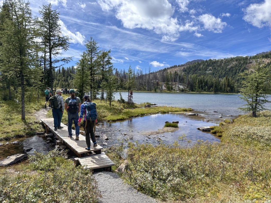 Hikers cross a bridge at Grizzly Lake