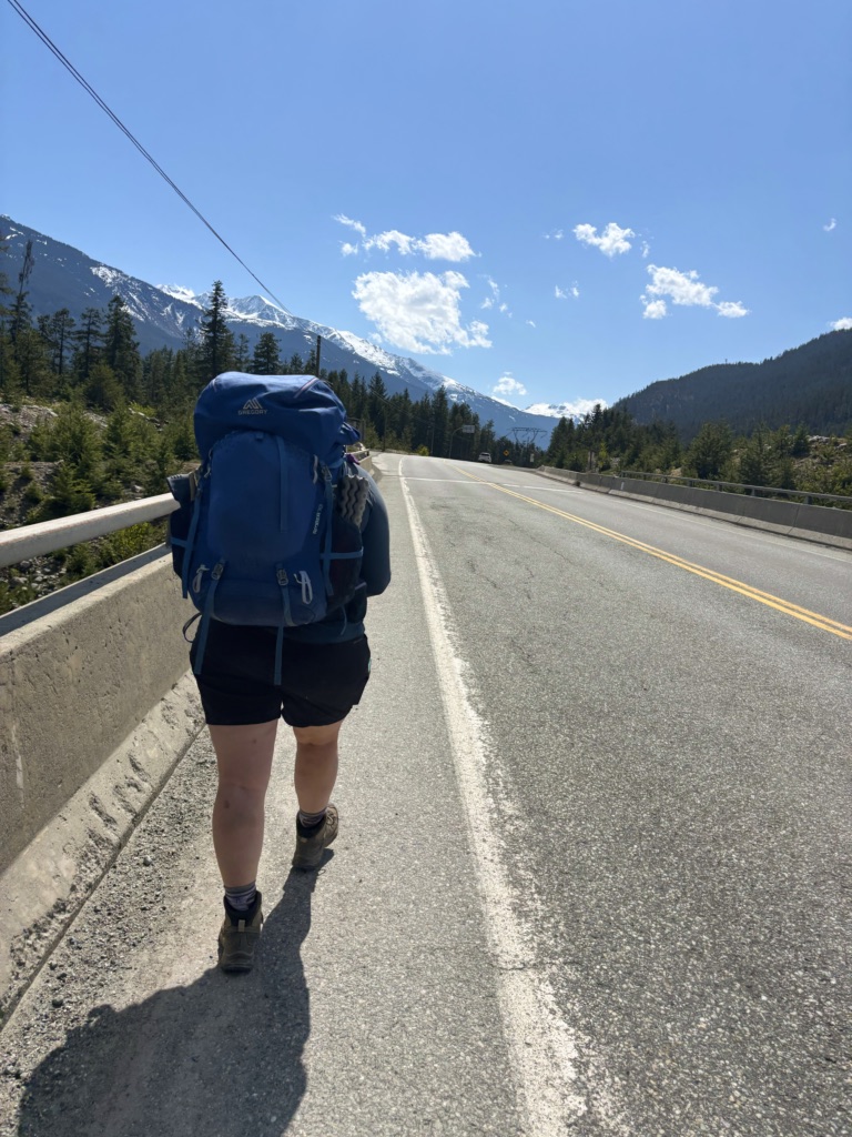 A hiker walks on the Sea to Sky Highway