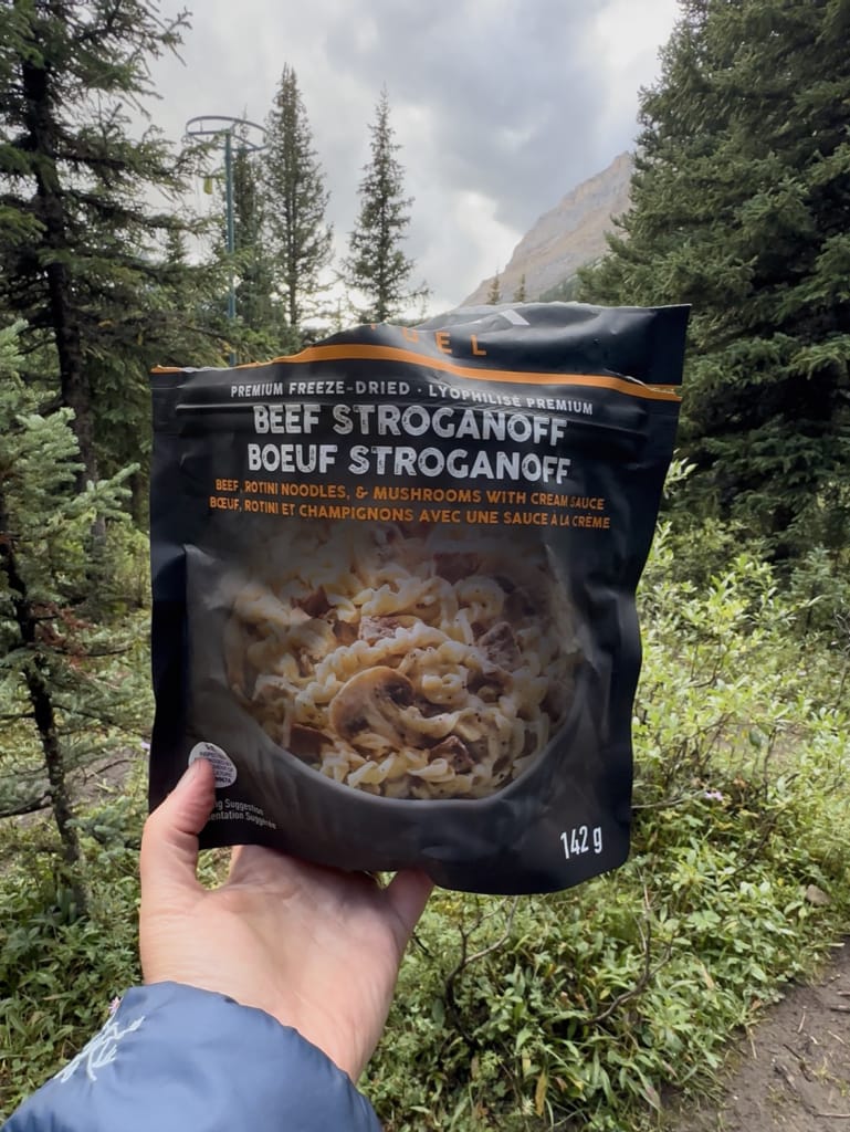 A hiker holds a package of Peak Refuel Beef Stroganoff
