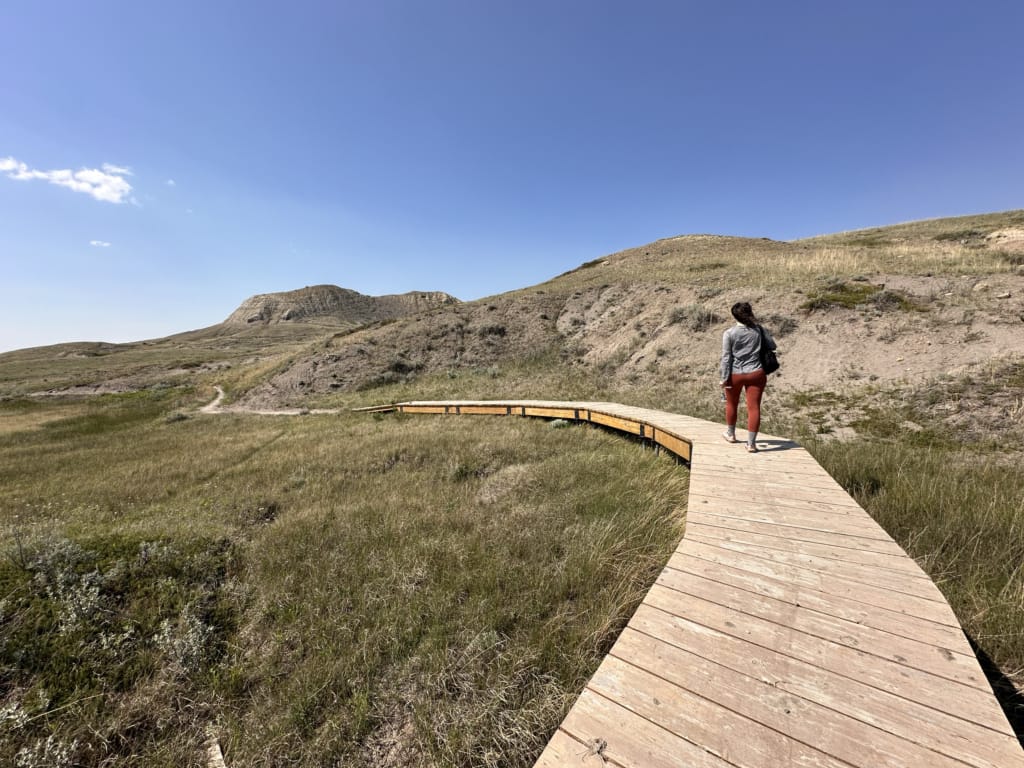A woman walks on a boardwalk in Grasslands National Park