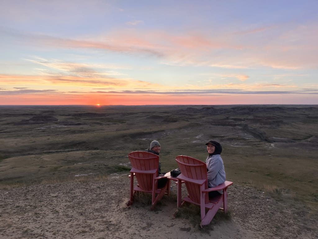 Two people bundled up to watch the sunset in Grasslands National park