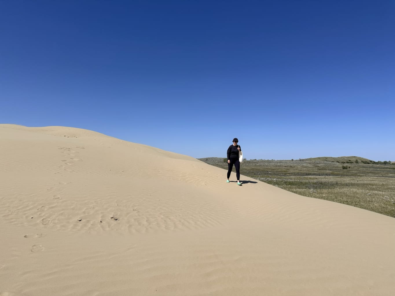 A woman walks on a sand dune at the Great Sand Hills, one of the best things to do in Saskatchewan
