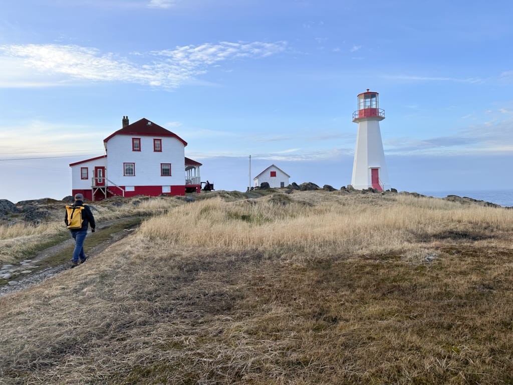 A hiker walks up to the Quirpon Lighthouse Inn