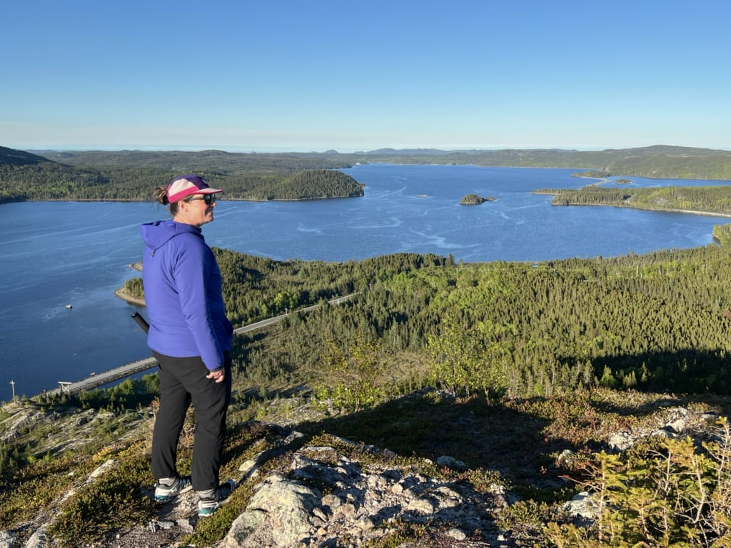 A woman stands on a rocky outcrop at Mill Cove Viewpoint in Terra Nova National Park near the Eastport Peninsula