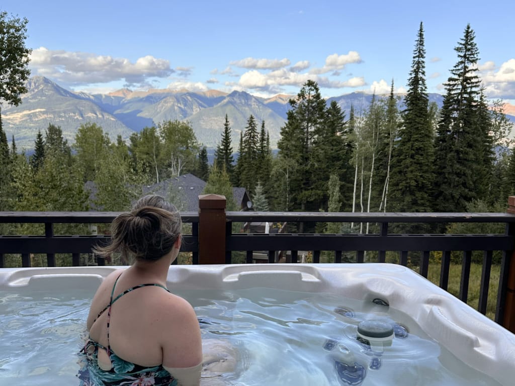 A woman in a hot tub looking at the mountains at Lush Mountain Accommodations in Golden