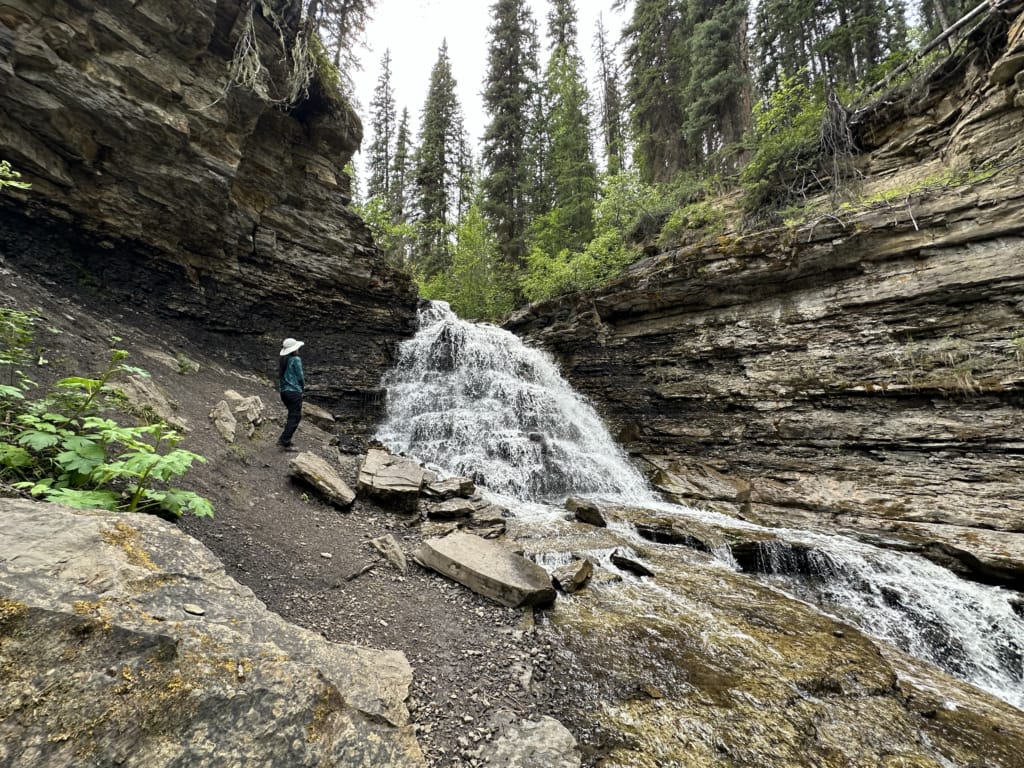 A hiker stands next to Quality Falls near Tumbler Ridge