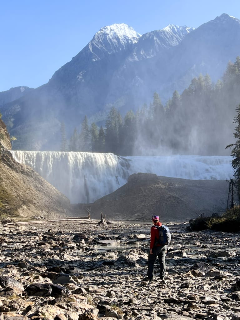 A hiker walks across the mud flats below Wapta Falls in Yoho National Park
